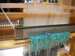The warp threaded through pattern and ground heddles, then through the reed.